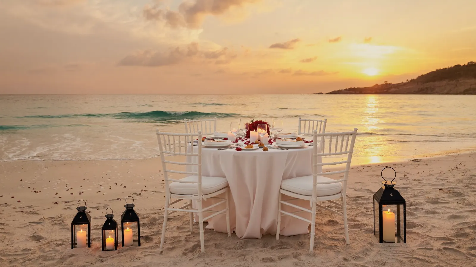 Jantar romântico à luz de velas na areia ao pôr do sol